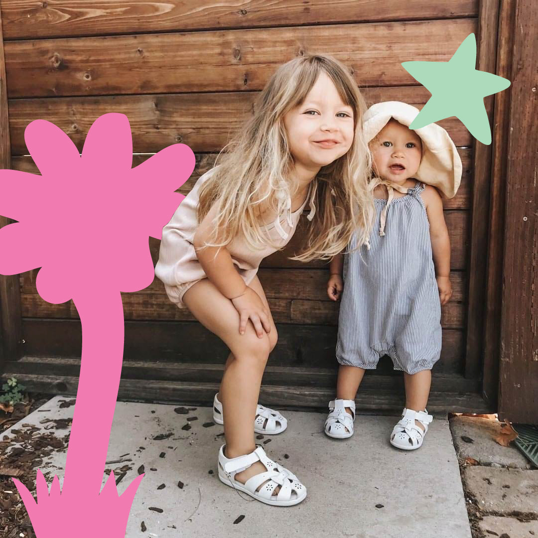 Two children wearing pediped shoes, sitting together on wooden steps